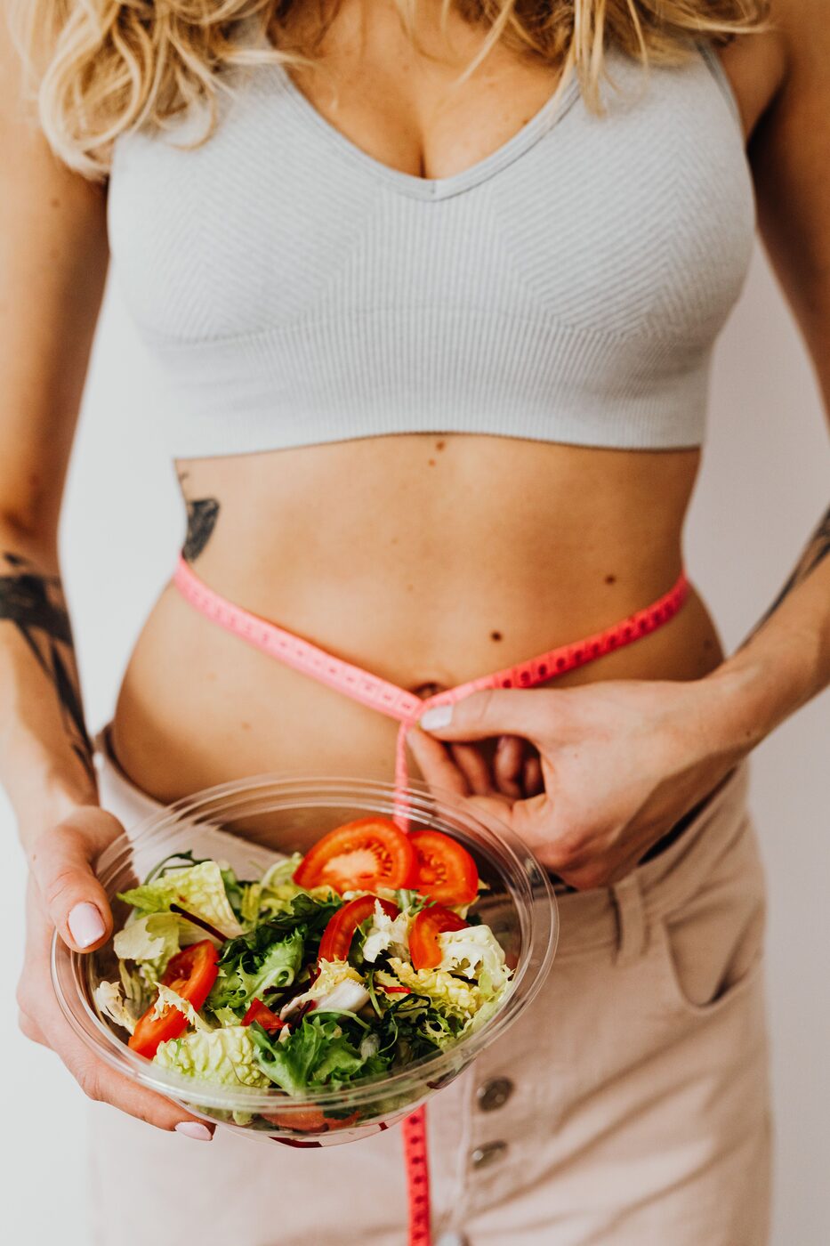 Bol de salade fraîche tenu à la taille, symbole de motivation pour perdre du poids